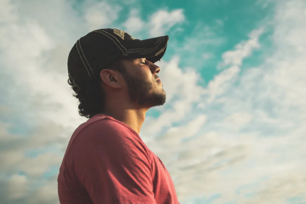 A man wearing a baseball cap enjoying the outdoors, with blue sky and clouds in the background. IBS dietitian in California and Europe