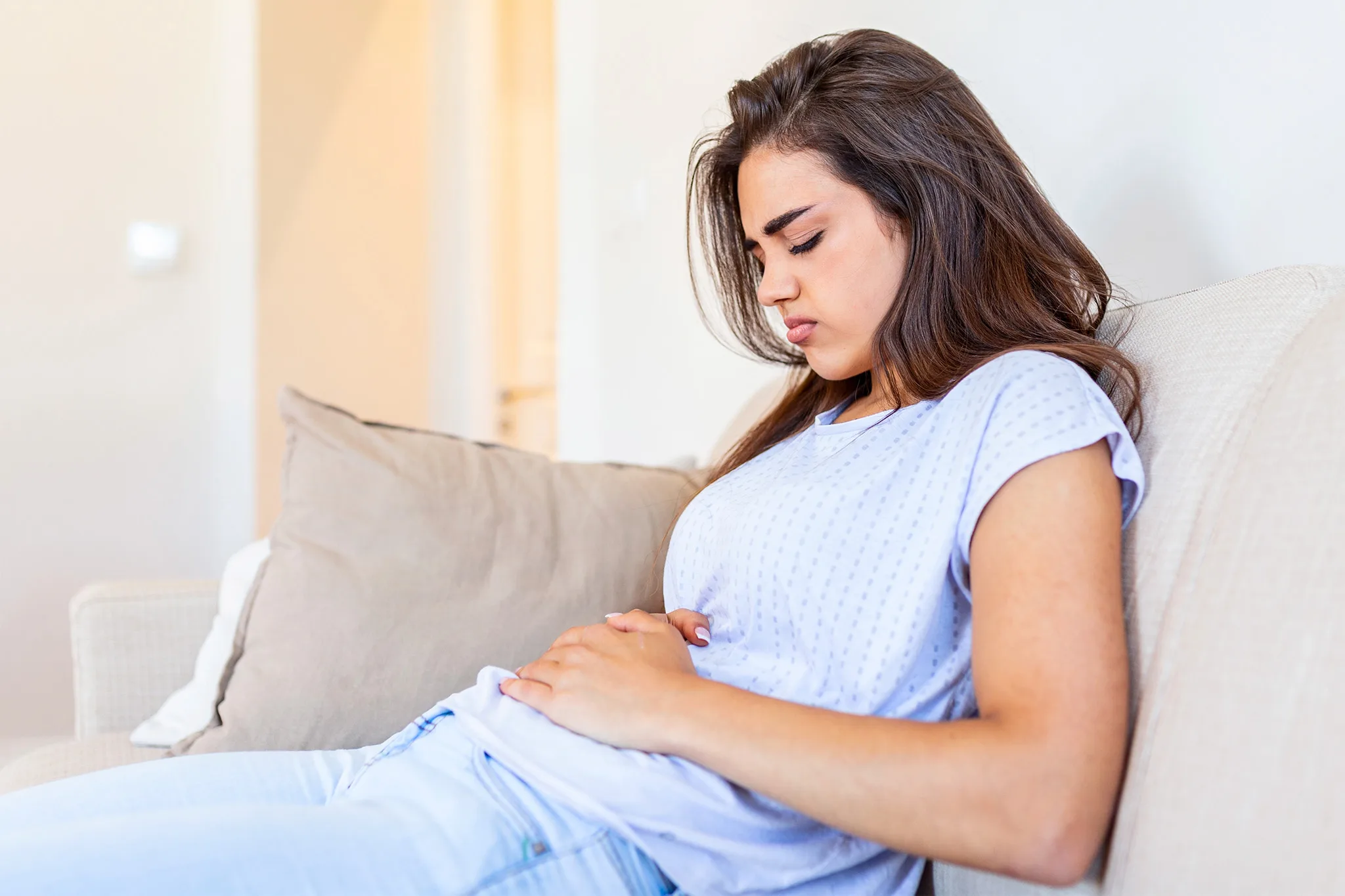 Girl with abdominal pain clutching her stomach. IBS dietitian in California and Europe 